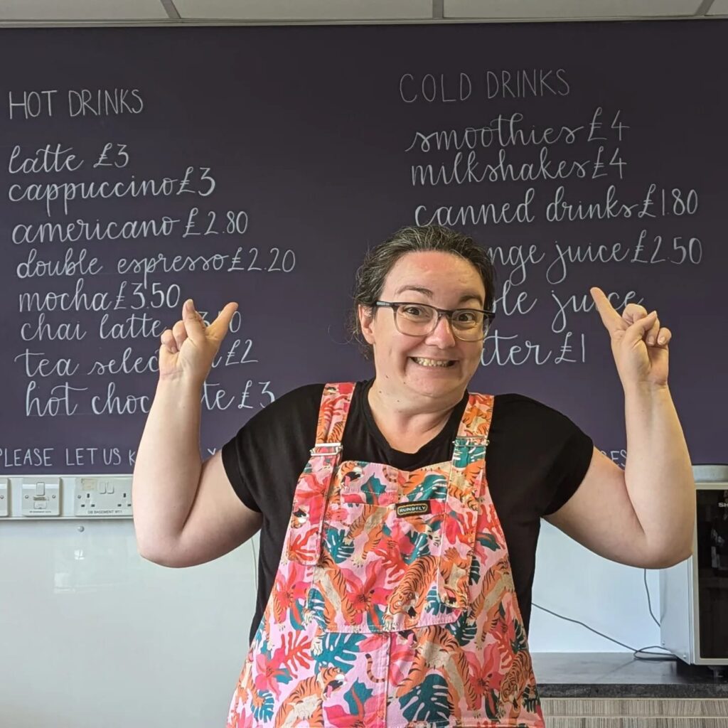 Emma, aka A Cornish Geek, stood in front of a menu which she hand lettered for Georgia's Voice's cafe